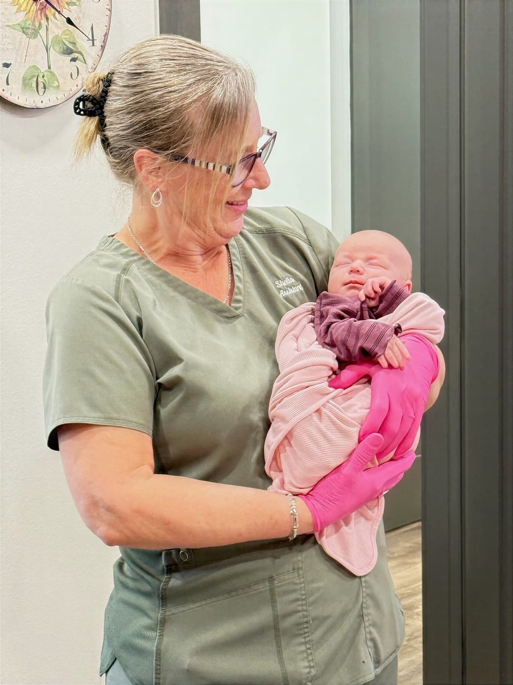 A Latched Beginnings team member gently cradling a swaddled newborn